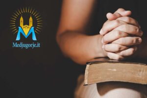 Persona che prega a mani congiunte sopra un testo sacro