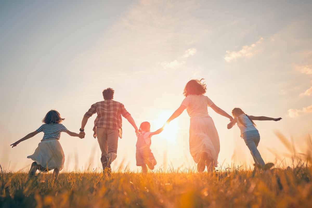Famiglia che corre su un prato durante un bel tramonto