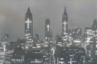 Certe immagini sembrano arrivare da un altro mondo. Non per distanza geografica, ma per distanza interiore. New York, 1956. Notte. I grattacieli del distretto finanziario illuminati in modo insolito: non pubblicità, non insegne. Croci.