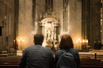 Coppia che prega insieme in una chiesa, illuminata dalla luce naturale