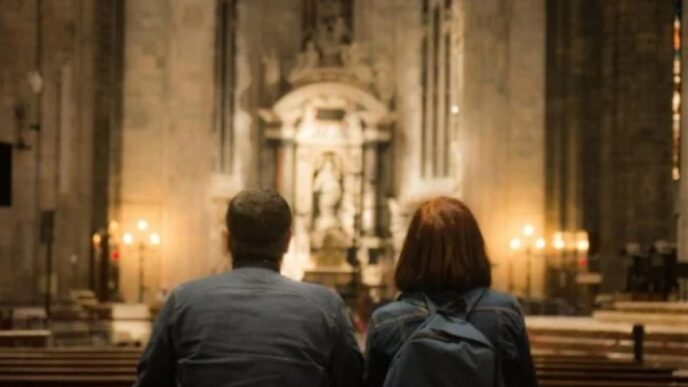 Coppia che prega insieme in una chiesa, illuminata dalla luce naturale