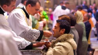 Fedele riceve la Comunione in ginocchio durante una celebrazione eucaristica
