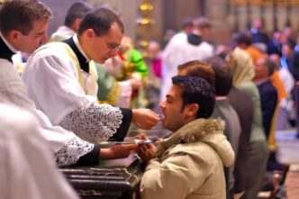 Fedele riceve la Comunione in ginocchio durante una celebrazione eucaristica