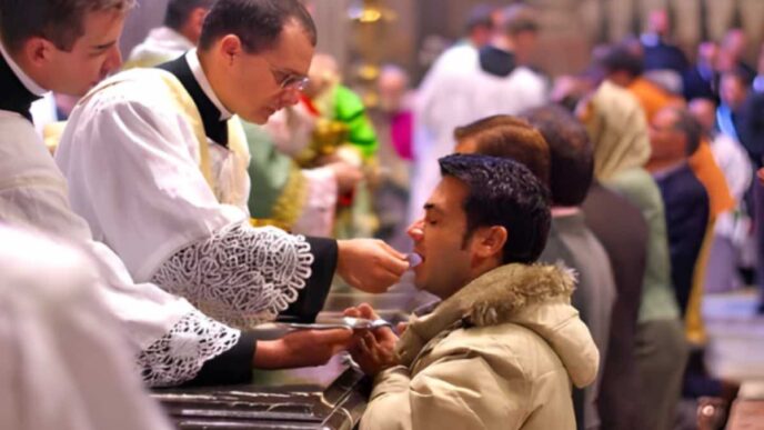Fedele riceve la Comunione in ginocchio durante una celebrazione eucaristica