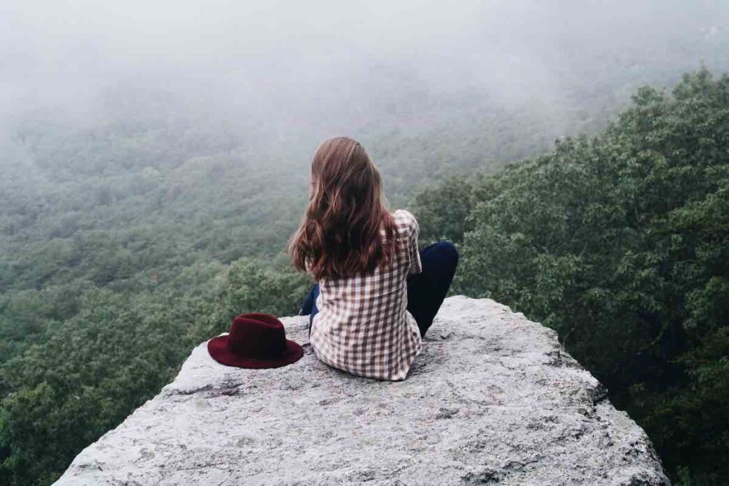 Persona che riflette meditativamente davanti a un paesaggio naturale