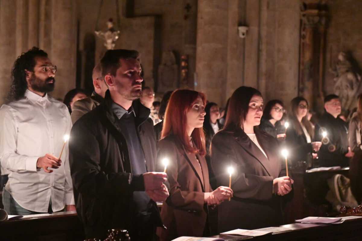 Comunità cristiana durante la celebrazione della Pentecoste con candele accese e inni sacri