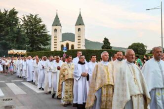 Processione eucaristica del Corpus Domini con ostensorio portato dal sacerdote sotto baldacchino tra fedeli in una via del paese