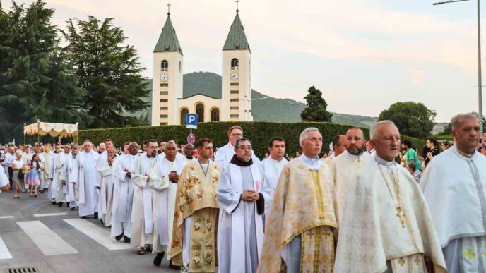 Processione eucaristica del Corpus Domini con ostensorio portato dal sacerdote sotto baldacchino tra fedeli in una via del paese