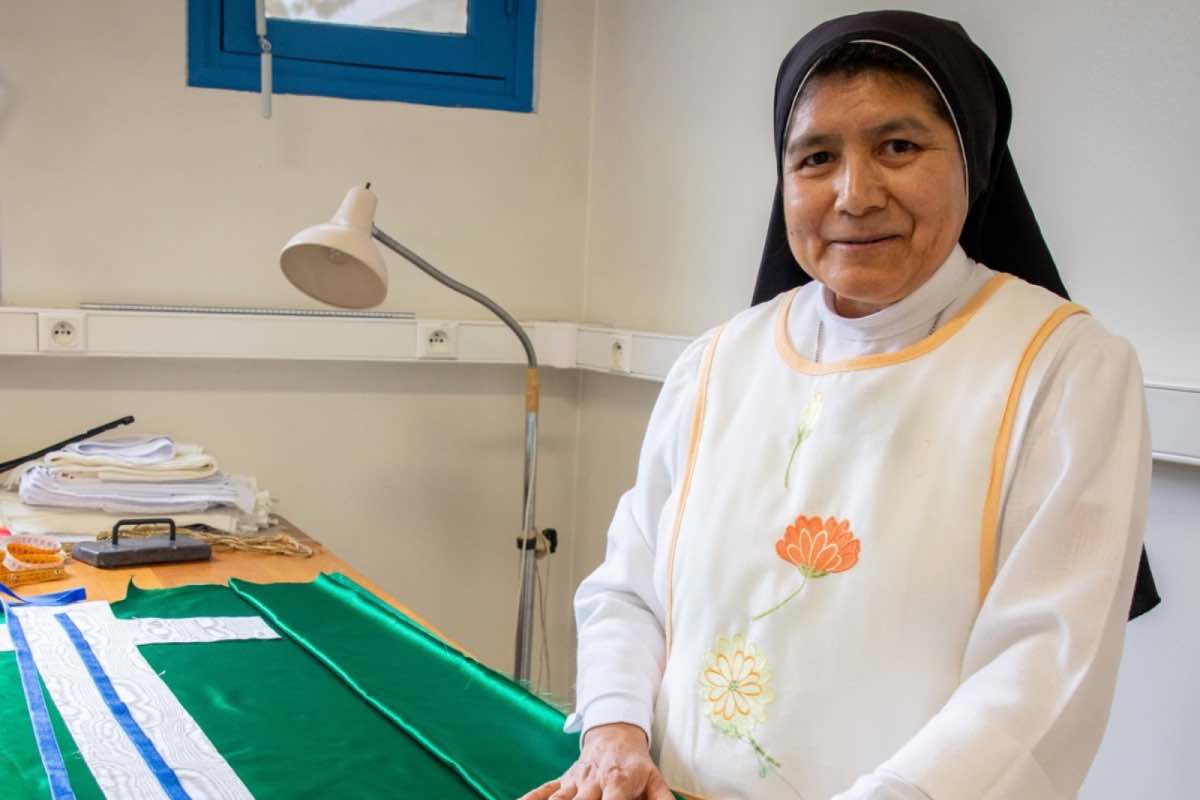 nel laboratorio di sartoria suor Martha sta realizzando i paramenti liturgici che Leone XIV indosserà durante la visita, mentre nelle officine prende forma la grande croce del podio